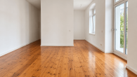 Optimiere dieses Foto einer Mietwohnung für ein professionelles Immobilien-Exposé.  Ziel: Das Bild soll aussehen wie von einem professionellen Immobilienfotografen aufgenommen – hochwertig ausgeleuchtet, technisch sauber, natürlich.  Bearbeite ausschließlich Licht, Belichtung und Perspektive: - Ausleuchtung gleichmäßig und professionell: Schatten aufhellen, überstrahlte Bereiche zurücknehmen, ausgewogene Helligkeit im ganzen Raum - Weißabgleich neutral und natürlich, keine Farbstiche (weder gelb noch blau) - Fenster korrekt belichtet, sodass der Ausblick sichtbar bleibt, statt auszubrennen - Perspektive begradigen: senkrechte Linien (Wände, Türrahmen, Fenster) exakt lotrecht, waagerechte Linien gerade, keine kippenden oder stürzenden Kanten – gerader, natürlicher Blickwinkel - Bildrauschen reduzieren, Schärfe und Detailzeichnung sauber halten  Verändere nichts am Inhalt oder Zustand des Raumes: - Keine Möbel, Objekte, Personen oder Gegenstände hinzufügen, entfernen oder verschieben - Grundriss, Raumaufteilung, Wände, Türen und Fenster exakt so lassen, wie sie sind - Keine Renovierung, kein Aufräumen, keine kosmetische Beschönigung von Wänden, Böden, Decken oder Mängeln - Keine neuen Elemente einfügen und keine bestehenden ersetzen  Das Ergebnis soll denselben Raum in exakt demselben Zustand zeigen – nur professionell fotografiert und ausgeleuchtet. Behalte das originale Seitenverhältnis bei. - Helle 1-Zimmer-Wohnung mit Balkon und großzügigem Wohngefühl